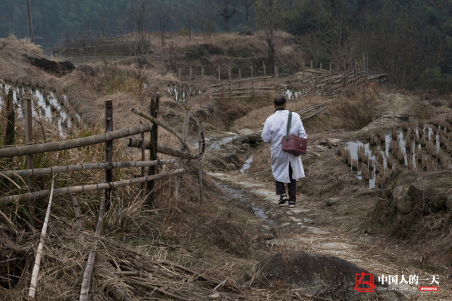 钟医生背着药箱行走在山路上的背影.