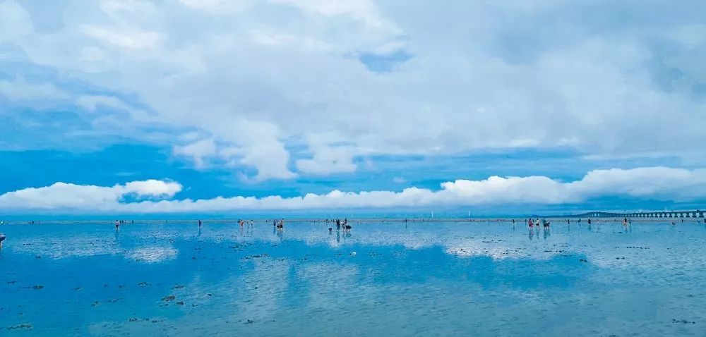 浦东新区新闻办说,临港东海大桥边的天空之镜海滩,蓝天白云一望无际