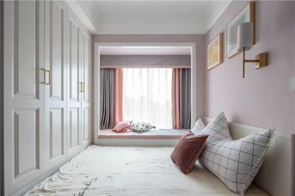 飘窗挨着床铺,垫上粉色的布垫,结合灰粉配的窗帘,呈现出一种温馨自然