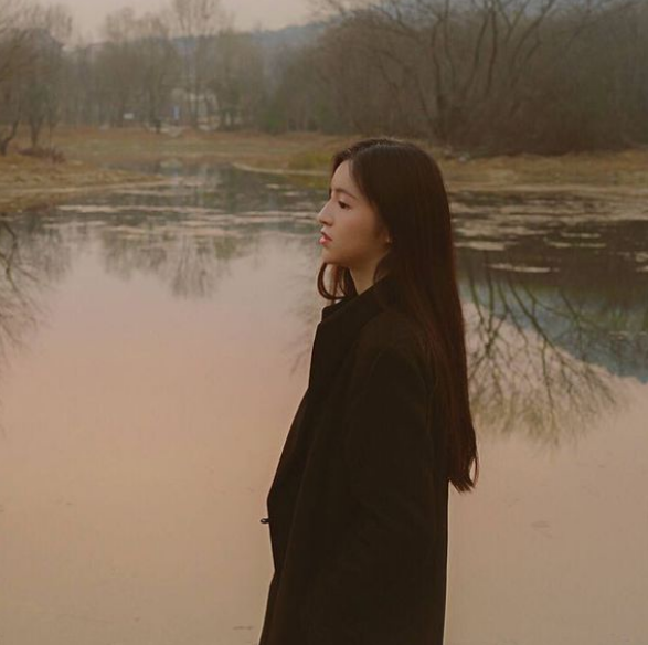 这张照片上的是一个女孩子,她站在湖边,穿了一件非常暖和的黑色大衣