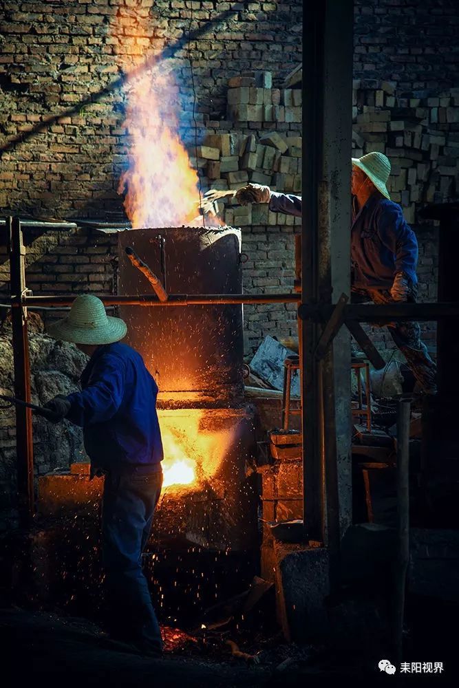 师傅们在高温环境下熔铁作业,将生铁块送到熔炉里经过高温熔化.
