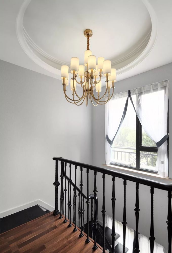楼梯间以铁艺扶手,顶上圆形的吊顶造型 黄铜质感的吊灯,也使得这个