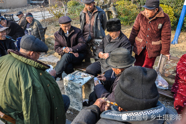 图为皖北农村老人打纸牌非常认真,旁边有村民围观.