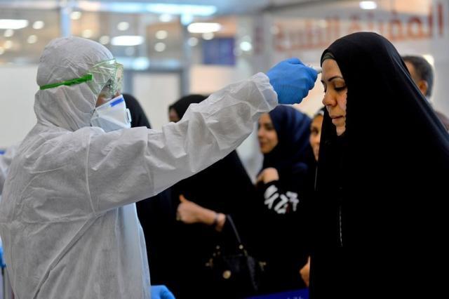 伊拉克奈杰夫机场,防疫人员在对一名从伊朗回到伊拉克的妇女进行