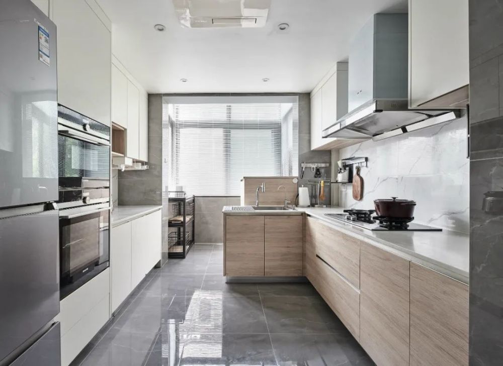 厨房在灰色抛光砖地面的基础,设置上充裕的操作台,木色与白色的定制