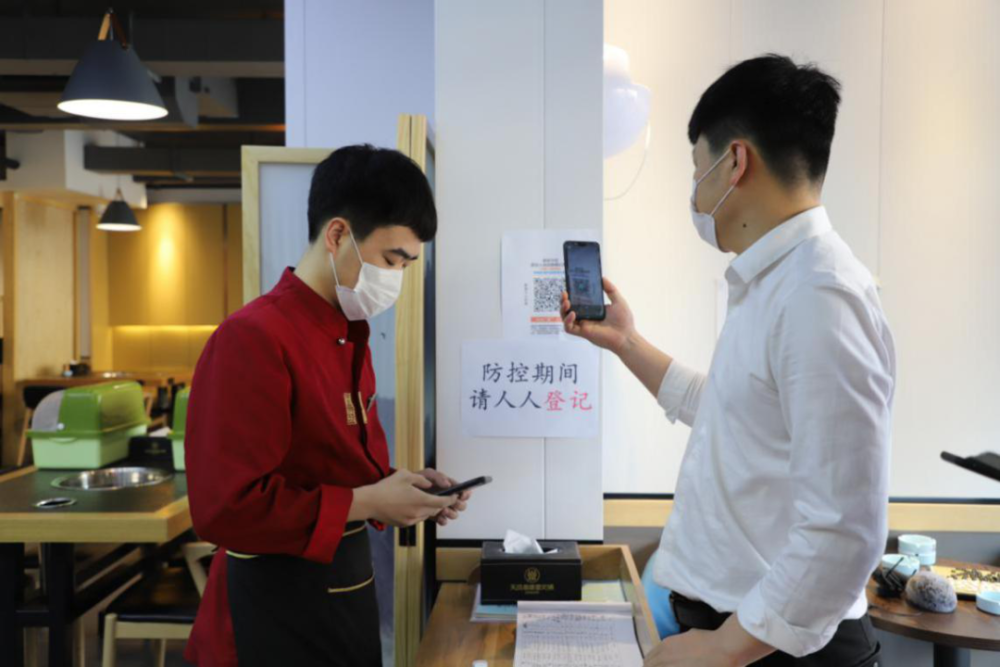 员工进行测体温,扫码后进店上班