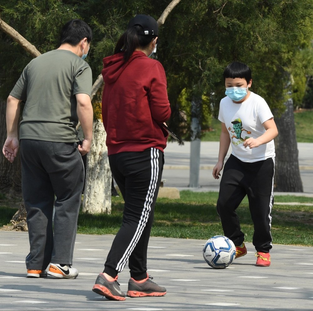 3月26日,龙潭公园,一名小学生和父母一起踢足球.