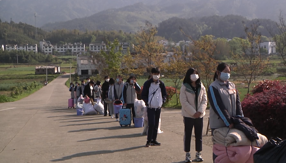 在婺源县江湾中学校门口,交警正在有序疏导来往车辆,学生们自觉间隔一