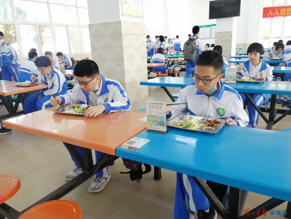 海南华侨中学食堂门口放置了温馨提示和指示牌.