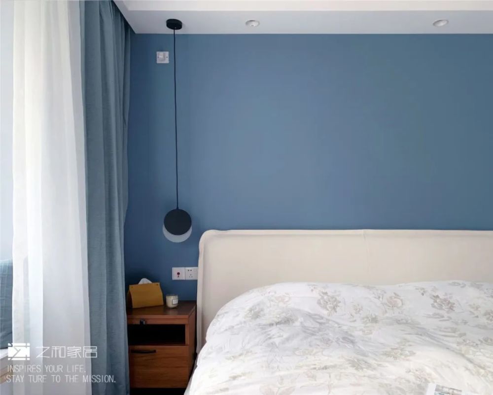 搭配柔软飘逸的窗帘和木质的装饰柜,白色的真皮床,灰蓝色的背景墙