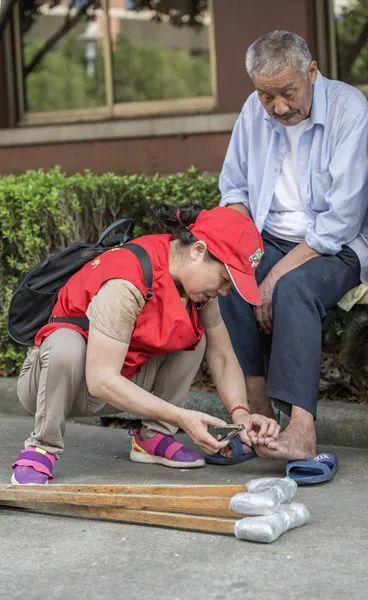 史丽琴正在为老人剪脚指甲