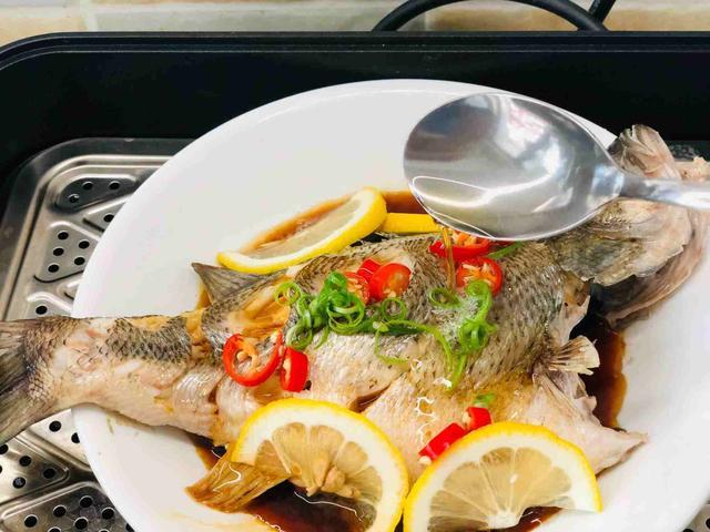 铺上柠檬做装饰,撒上葱花和辣椒圈,淋上热油.6.淋上柠檬蒸鱼酱油.