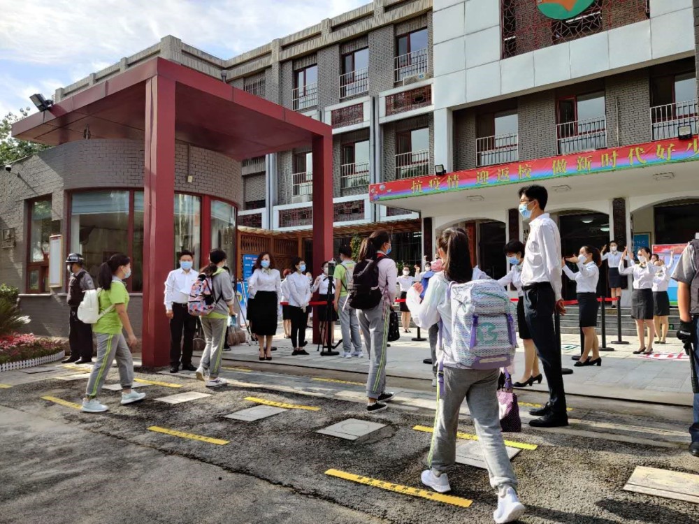 北京光明小学的学生走进校门,老师们以《你笑起来真好看》手语舞欢迎