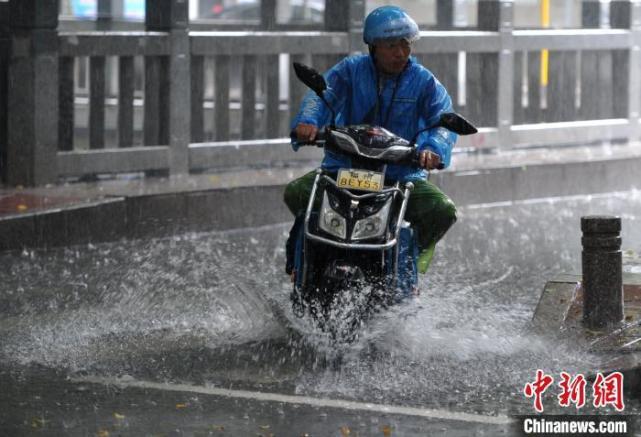 6月2日,福州外卖骑手经过积水路面.张斌 摄