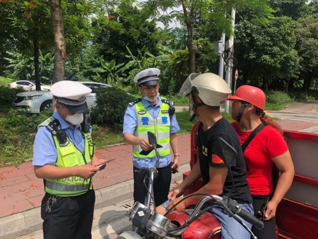 交警对没有佩戴符合安全标准的头盔的摩托车骑乘人进行现场教育.