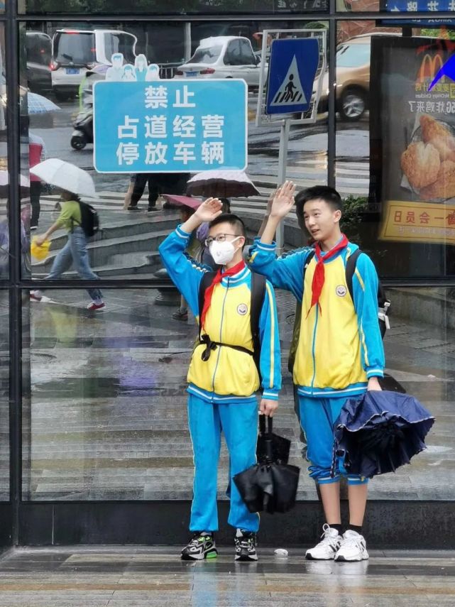 暴雨中,两个小学生的升旗礼