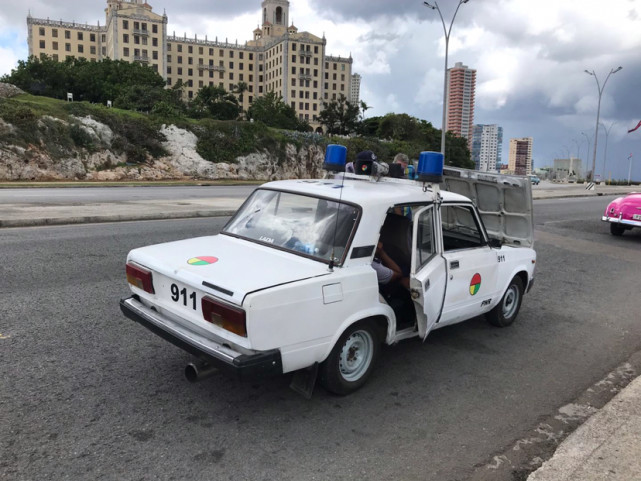 这是一辆警车,一辆白色老式汽车上,放两个蓝色"小水桶",车后面写着