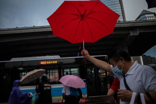 6月18日,一位路人高举着一把红色雨伞从国贸桥下经过