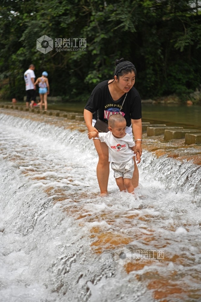 2020年7月5日,在江西省上饶市铅山县太源畲族乡水美村,游客在河里戏水