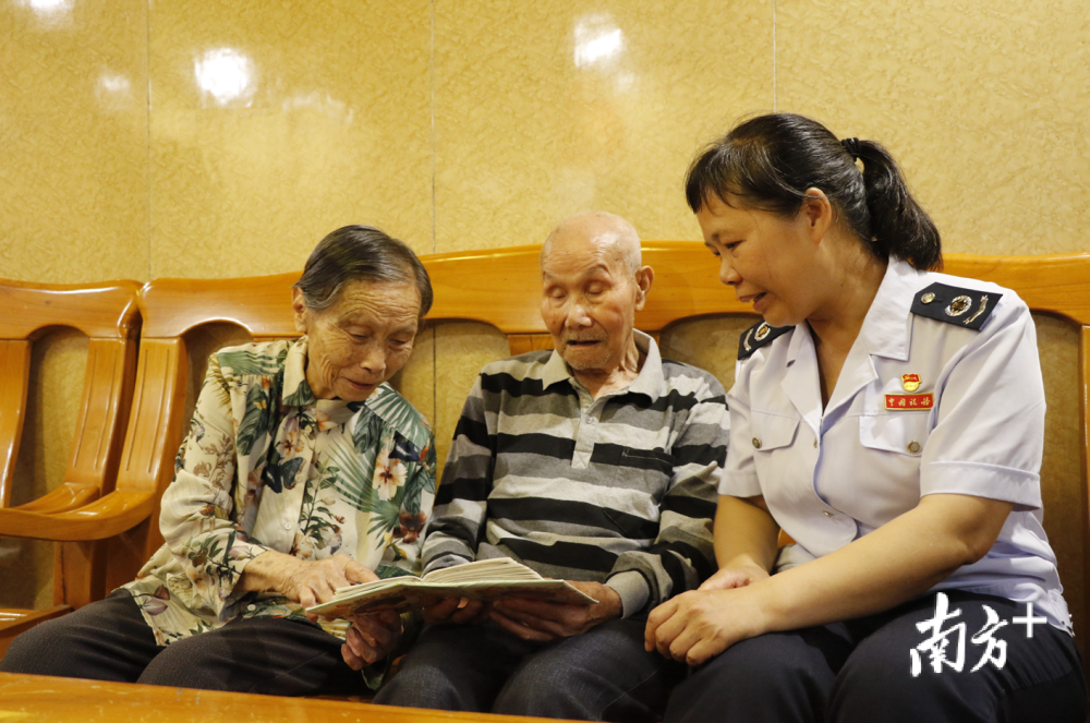 成隆灿(中)翻阅相册,给妻子邓美容(左,儿媳(右)吴志榕讲述当年的故事