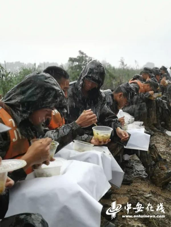 抗洪子弟兵满身泥泞在雨中吃午饭