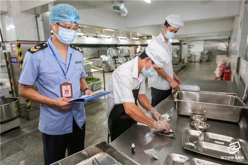 南海实验中学食品安全检查,食堂工作人员用试纸检测餐具表面洁净度.