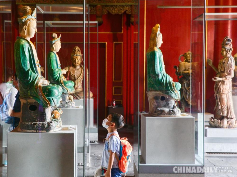 7月21日,游客在参观北京故宫博物院慈宁宫展厅的雕塑文物.