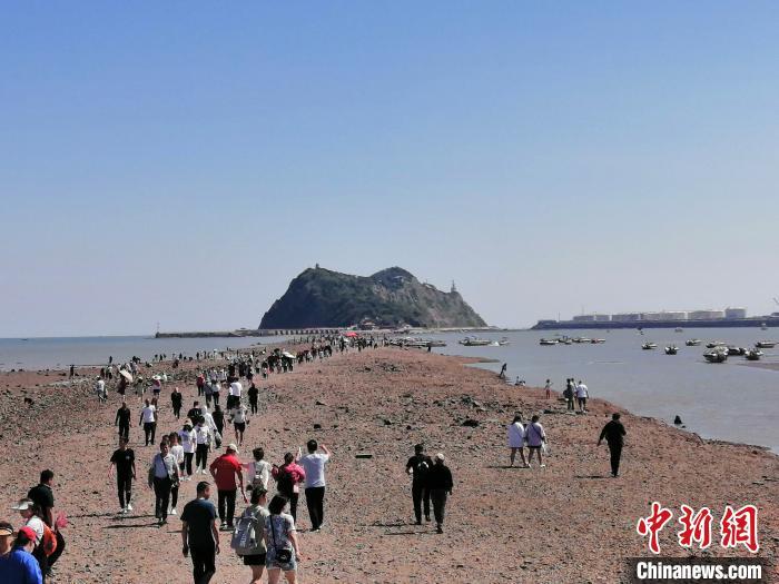 落潮时,锦州笔架山"天桥"完全显露出来,游客沿着"天桥"走向笔架山.