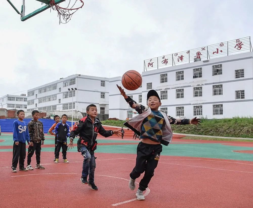 8月13日,布拖县阿布泽鲁小学内正在夏令营中的孩子们在校园新操场上