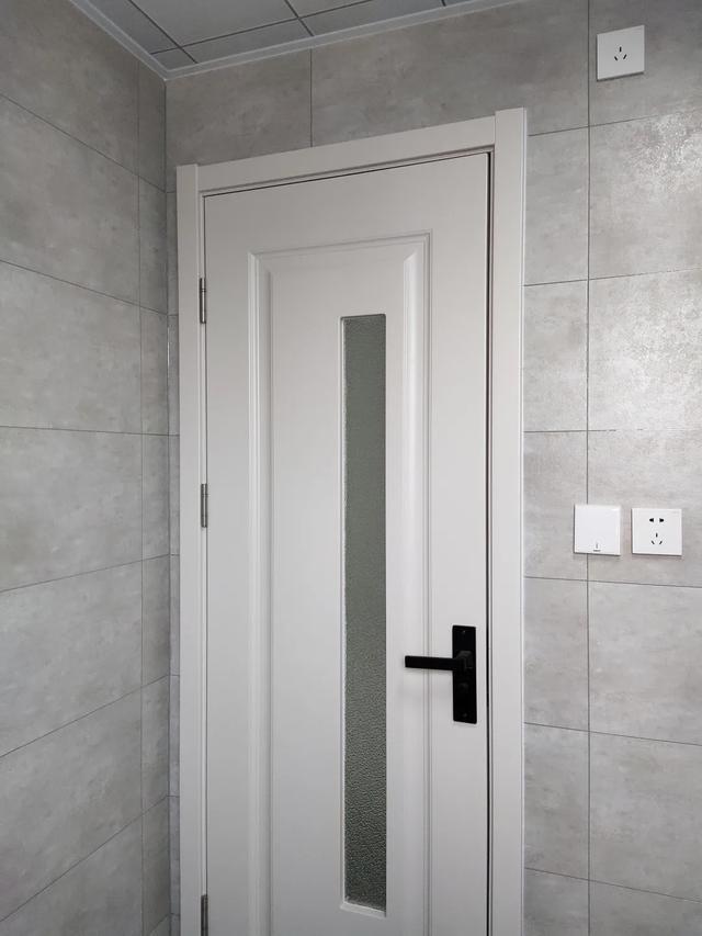 卫生间门选用干净的奶灰色木门,搭配磨砂玻璃,与浅灰咖色瓷砖相衬.