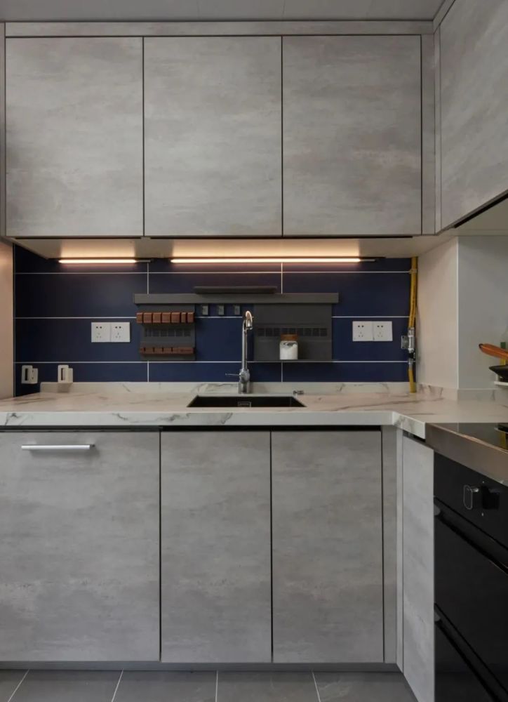 厨房,灰色瓷砖地面搭配水泥灰岩板橱柜门,深蓝色的墙面瓷砖与暖光
