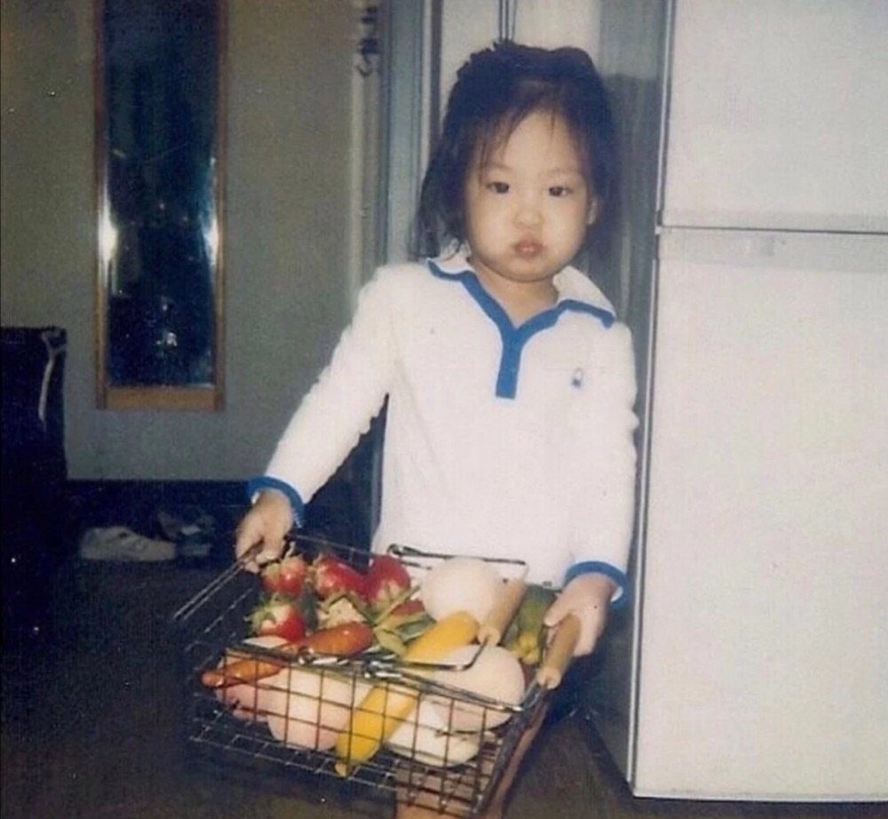 jennie小时候的脸又圆圆胖胖的像个小饺子,手里还拿了一堆蔬菜水果
