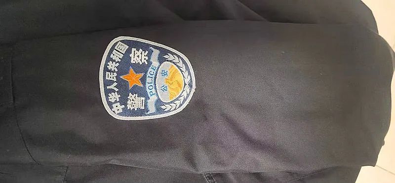 一名身穿警用大衣的男子,大衣上有人民警察警用臂章(没有警衔和警号)