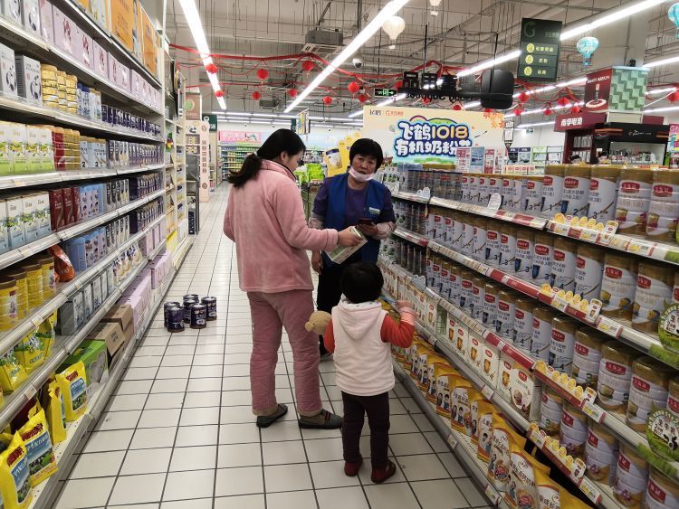永平路一家超市内,导购员向顾客推销国产奶粉