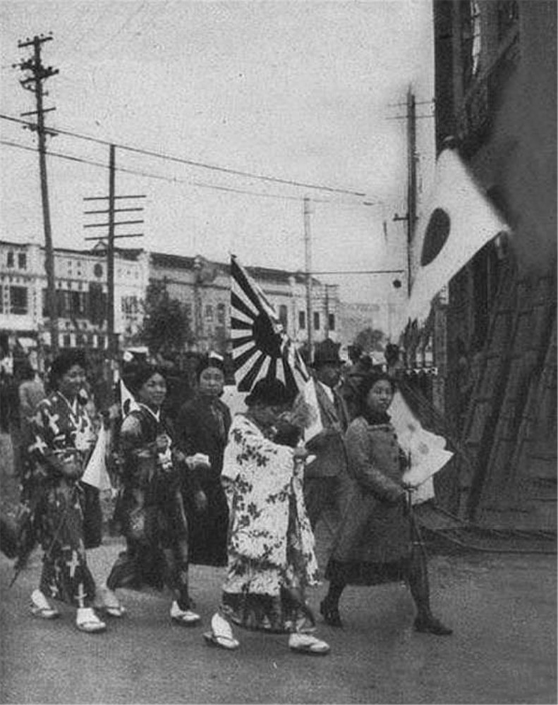 侵略南京的日本鬼子.这些举着日本旗帜的女人,就是日本士兵的帮凶.