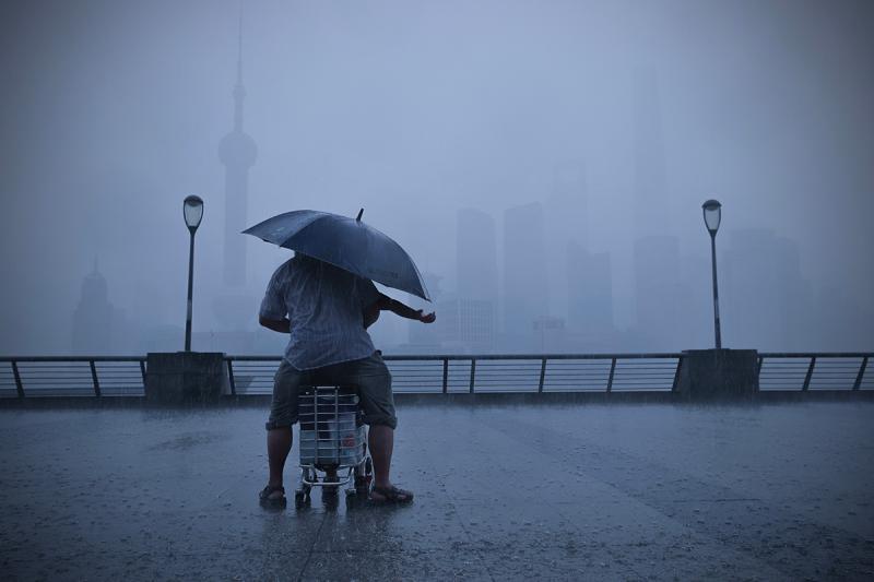 一场暴雨突如其来,一位老人撑伞罩着一名小朋友,小朋友伸出手接雨水