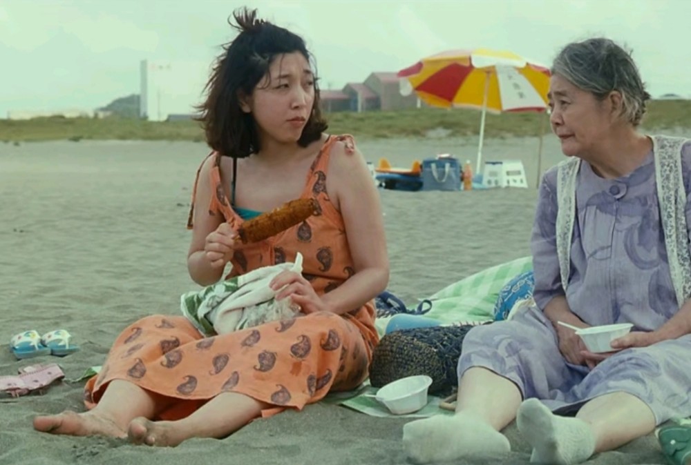 一家人去海边玩,沙滩看起来很干净,柴田信代和奶奶柴田初枝坐在沙滩之