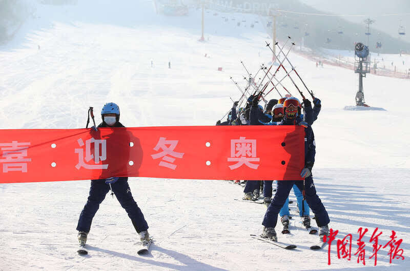 12月27日,北京平谷渔阳国际滑雪场,冰雪健儿展开喜迎冬奥的横幅合影