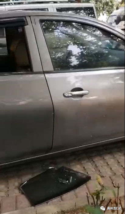 一辆咖啡色的小汽车停放在停车位上,后面的车窗被砸掉,整块的玻璃掉落