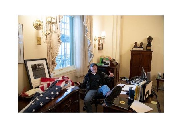 一名暴乱参与者坐在美国众议院议长佩洛西的办公室椅子上摆拍照片
