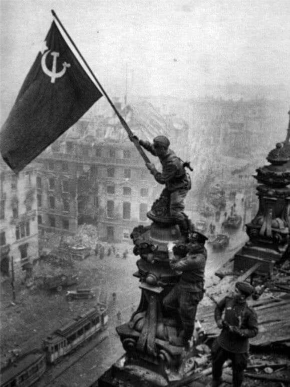只见一面巨大的红色镰刀锤子旗在德国国会大厦上方升起,狠狠地插进了