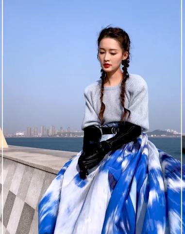 工作人员为李沁搭配了一双黑色长筒皮手套,单穿一件毛衣配长裙,坐在