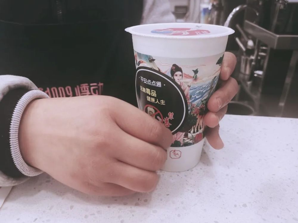 悸动烧仙草奶茶店店员正将禁毒贴纸粘在杯身上