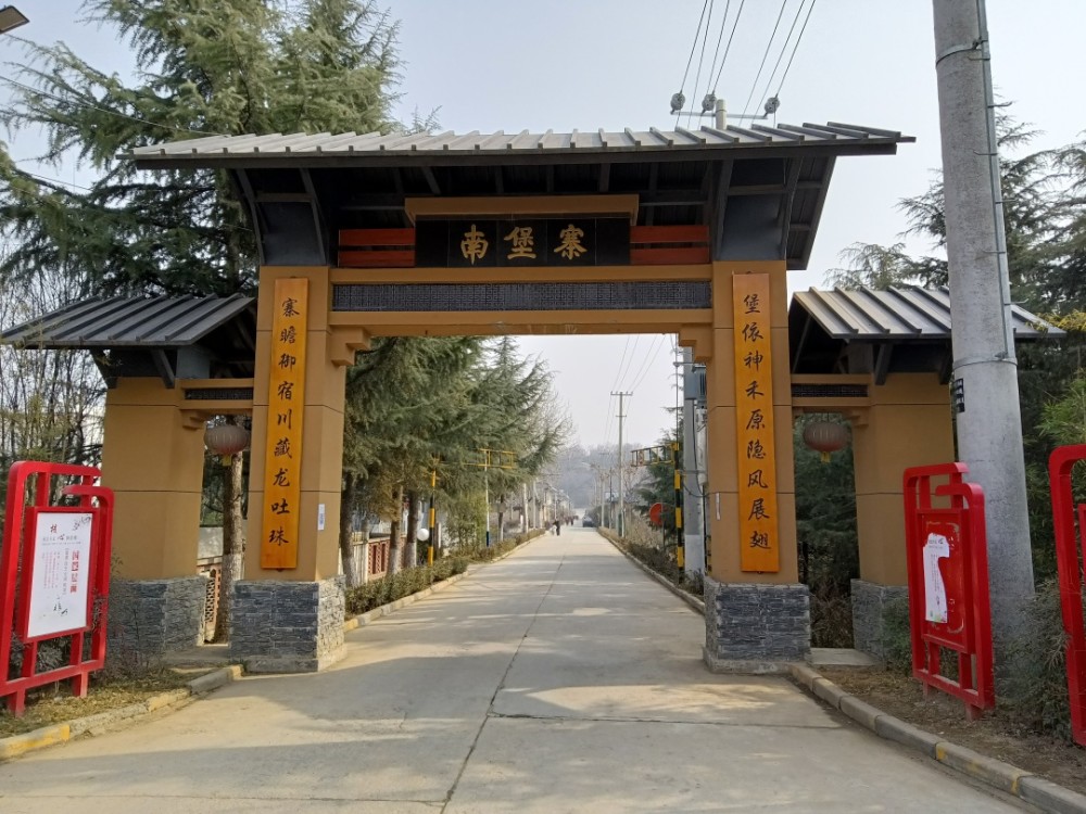 南堡寨村新村村口大门一副对联告诉了我答案——" 堡依神禾原隐风展翅