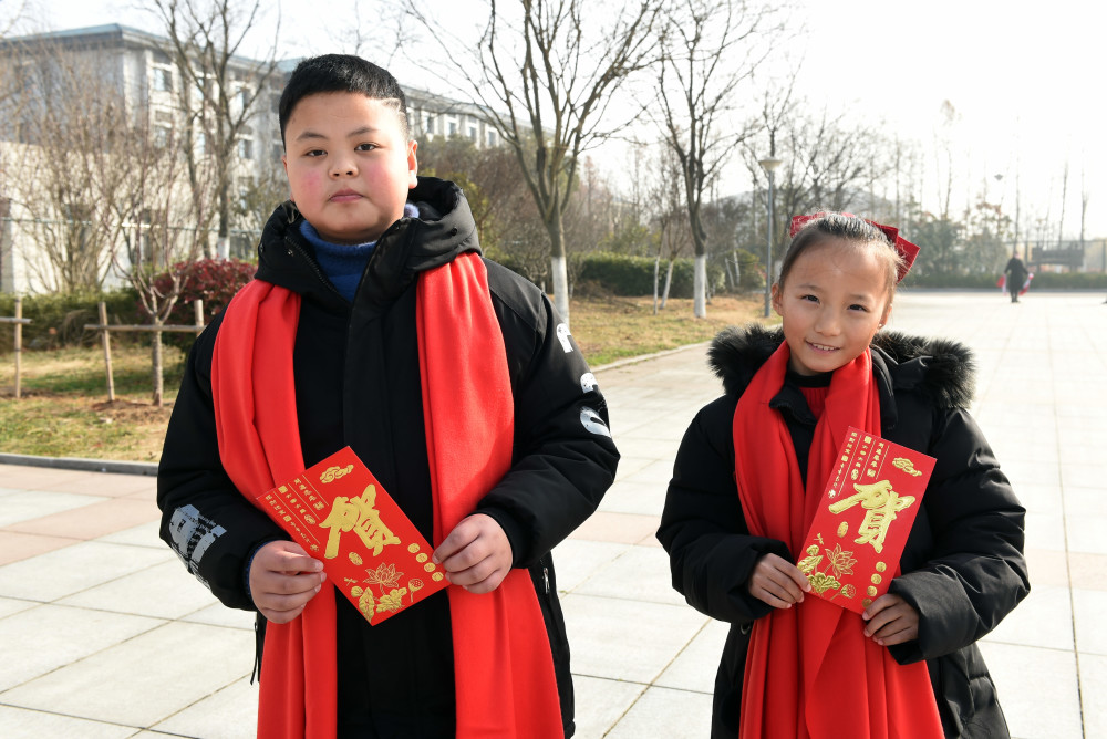 2月3日,凤阳县小岗村村民周浩天(左)和周可佳展示自家领取的分红红包.