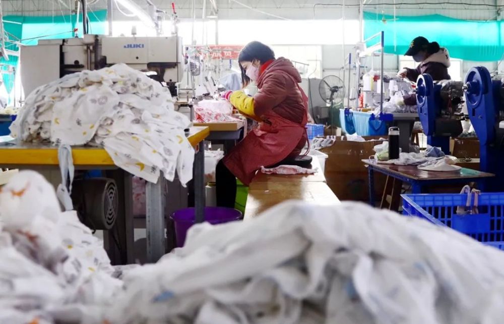 1月13日,在融安县汇鑫针织服装厂生产车间内拍摄的工人缝制童装场景.