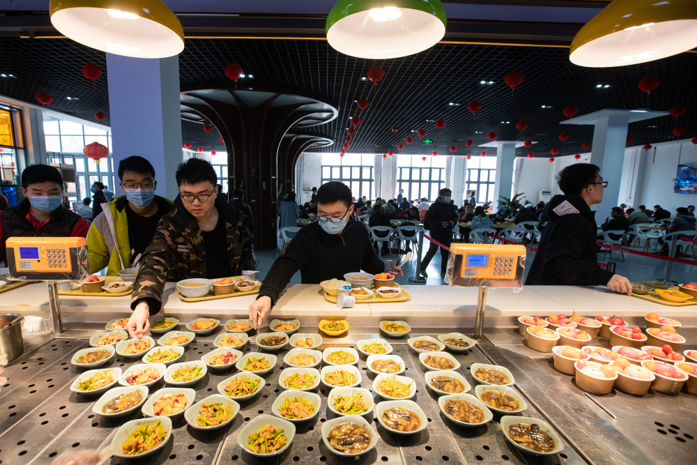 2月11日,在四川大学望江校区东二食堂,就餐的同学们排队取餐.