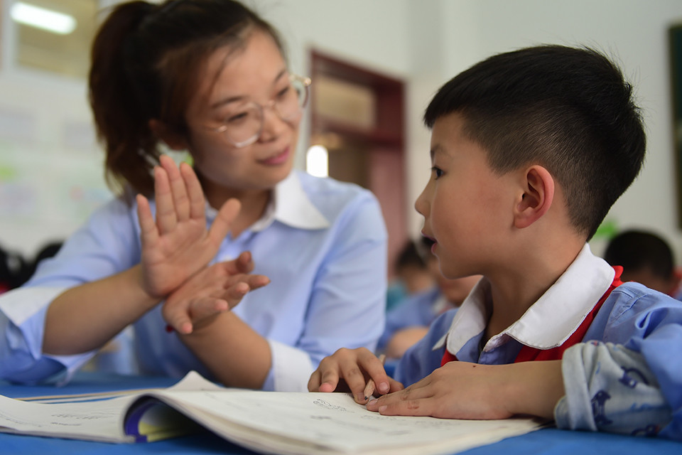 一小学学生在老师的指导下完成课后作业(新华社记者 王民/图)