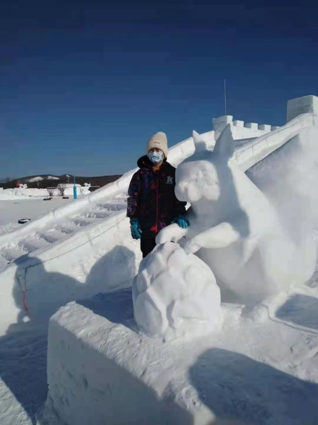 2021年2月17日,游客在内蒙古根河敖鲁古雅冰雪乐园与雪雕合影.