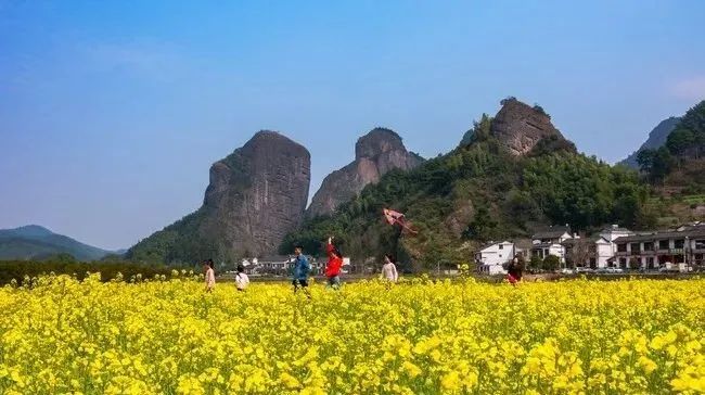 2月21日,新宁县崀山镇石田村,小学生正在油菜花地里喜戏追逐,放飞春天